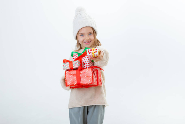 cute little kid in winter hat with boxes of gifts isolated on a white background - Photo, image