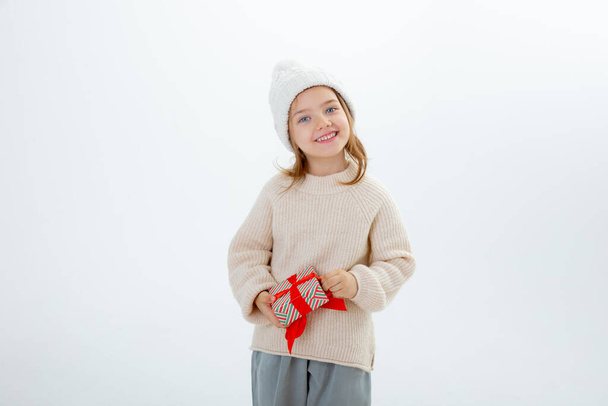 schattig klein kind in de winter hoed met dozen van geschenken geïsoleerd op een witte achtergrond - Foto, afbeelding