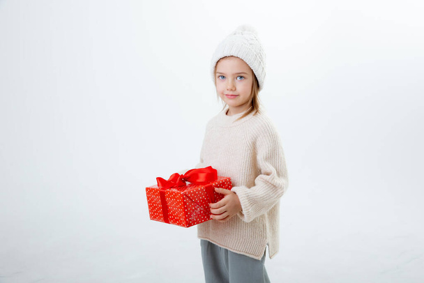 cute little kid in winter hat with boxes of gifts isolated on a white background - Фото, зображення