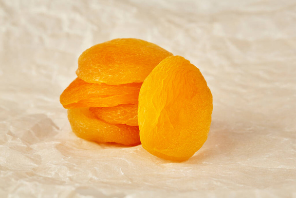 A stack of dried apricots lies on top of each other on white crumpled paper - Foto, imagen