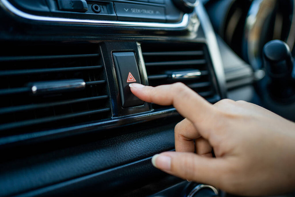 Κλείστε το χέρι πατήστε το φως έκτακτης ανάγκης στο αυτοκίνητο. Πατήστε το κουμπί έκτακτης ανάγκης για το ανοικτό προειδοποιητικό σύμβολο προειδοποίησης φως έκτακτης ανάγκης έξω από το αυτοκίνητο πλευρά. - Φωτογραφία, εικόνα