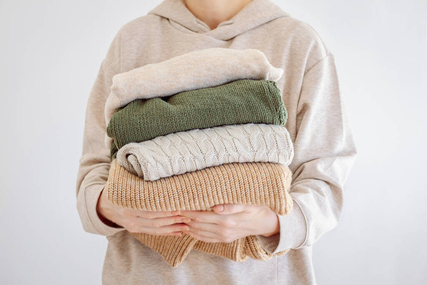 Womans hand holding a stack of clothes. Clothes Donation, Renewable Concept.Preparing Garment at Home before Donate - 写真・画像