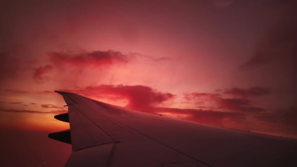 Dramatische roze lucht met pittoreske wolkenlandschap en vleugel van het vliegtuig vliegen er tussen - Video