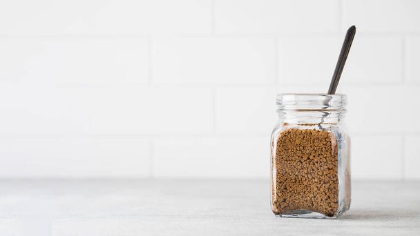 Glass jar with instant coffee with a spoon on a light background. Copy space. - Foto, immagini