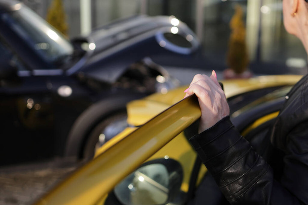 A woman looking at a car accident between her yellow car and a black car - 写真・画像