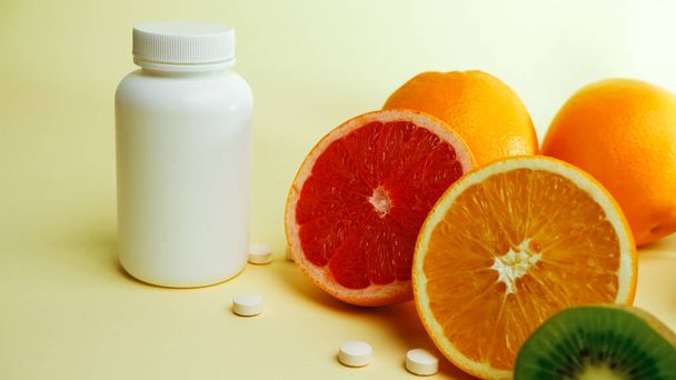 Vitamins. Medical concept. Pharmacy or natural. White bottle with vitamins, scattered pills. Juicy citrus fruit slices. lemon. Orange. Grapefruit. - Valokuva, kuva