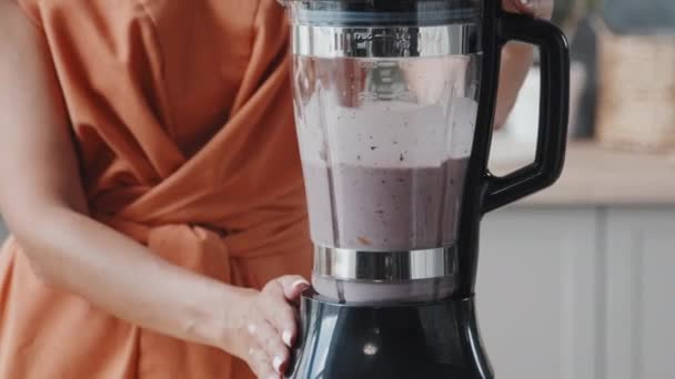 Mid-section tracking shot of unrecognizable young woman making delicious smoothie in blender in kitchen - Footage, Video