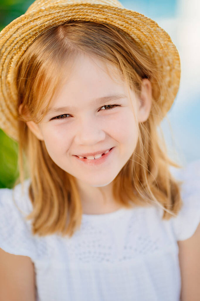 portrait of a happy little girl with blonde hair in a straw hat.  - Photo, Image