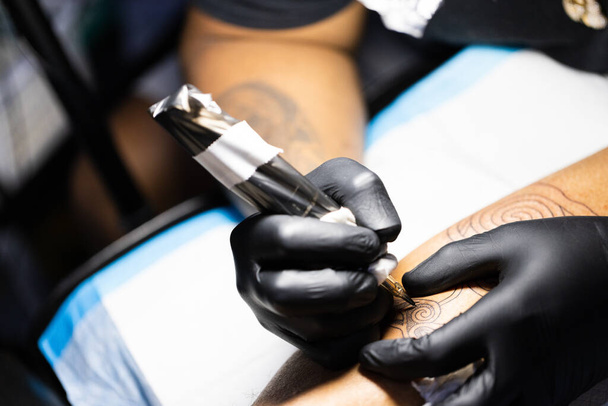 Чоловічі руки в чорних рукавичках з татуювальною машиною. крупним планом
. - Фото, зображення
