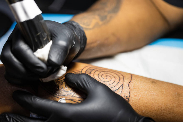 Manos del artista del tatuaje en guantes negros ocupados con el trabajo en la tienda de tatuajes.  - Foto, imagen