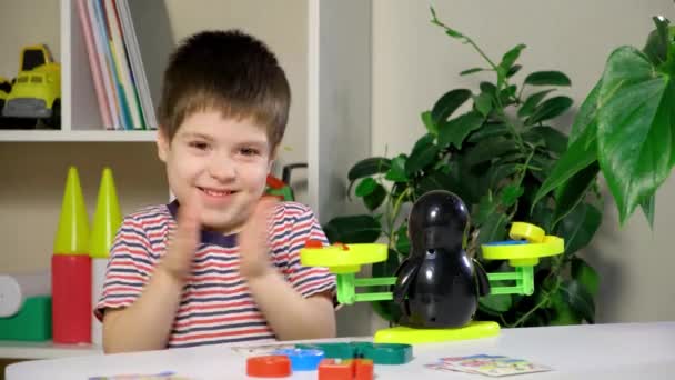 A preschool boy learns numbers, weighs numbers on a penguin scale - Footage, Video