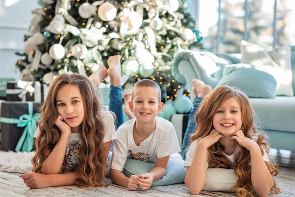 Children at Christmas tree and fireplace on Xmas morning. Family with kids celebrating Christmas at home. Boy and girls opening presents. Holiday gifts for kids. - Foto, Imagem