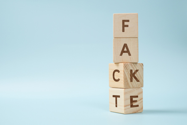 Fact or Fake concept, Wooden cube change the word, April fools day Concept over blue background - Фото, изображение