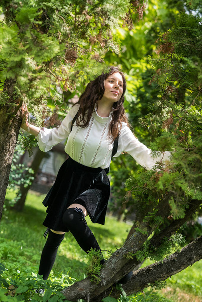 retrato de una mujer usa blusa blanca y falda negra con estilo cerca del árbol verde, parque de la ciudad - Foto, Imagen