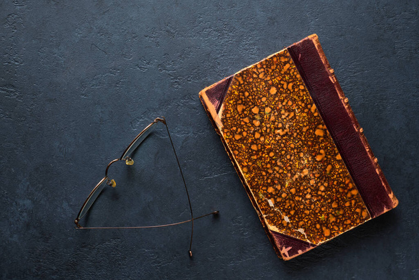 Old antique book and spectacles on black background closeup with copy space - Фото, зображення