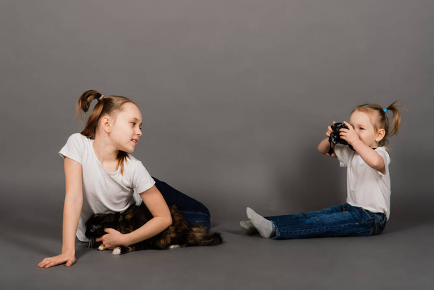 Sister taking photo with the camera of her sister in studio - Fotó, kép