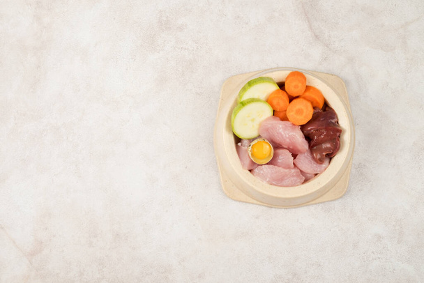 A bowl of natural products for feeding pets. Meat, liver, vegetables, quail egg. View from above. Copy space. - Foto, Imagem