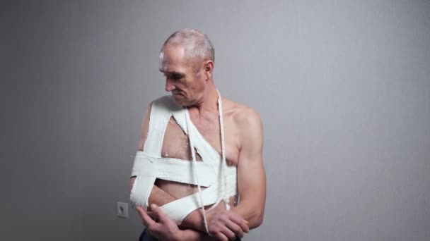 Senior mit Verband untersucht gebrochene Schulter an Wand - Filmmaterial, Video