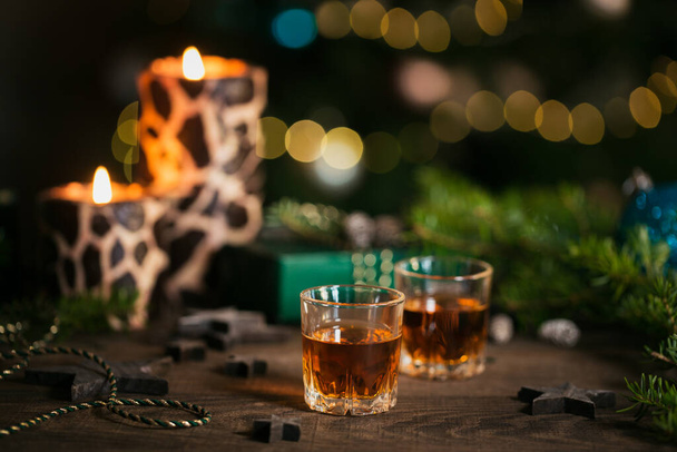Whiskey, brandy or liquor shot and Christmas decorations on wooden background. Winter holidays concept. - Foto, Imagen