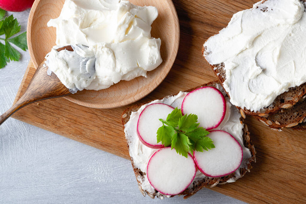 Home made rye bread on a wooden cutting board with curd cheese - Photo, Image