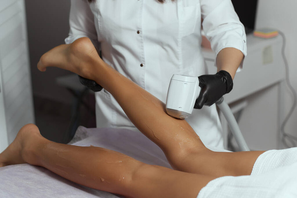 Young African woman getting laser hair removal on her thighs. - Φωτογραφία, εικόνα