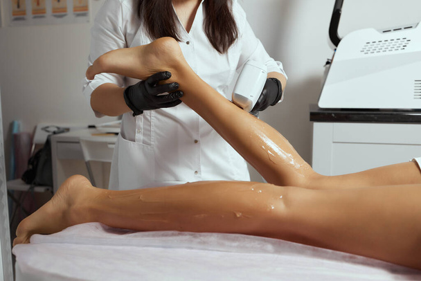 Young African woman getting laser hair removal on her thighs. - Photo, Image