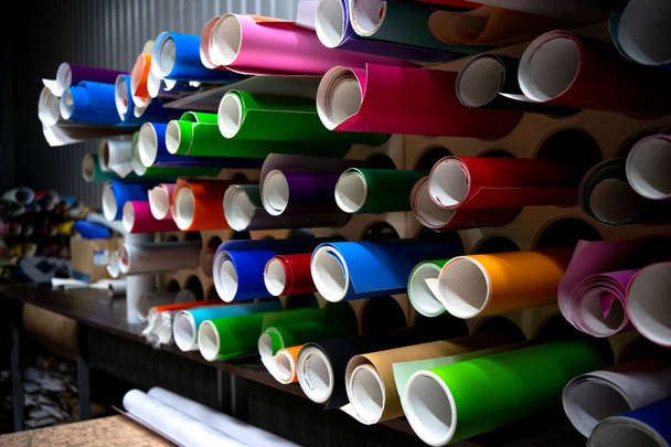 The self-adhesive film is in rolls on the shelves of production.Multicolored vinyl films. - Photo, Image
