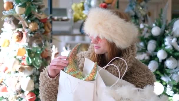 Зимняя распродажа: девушка в зимней одежде и солнцезащитных очках - Кадры, видео