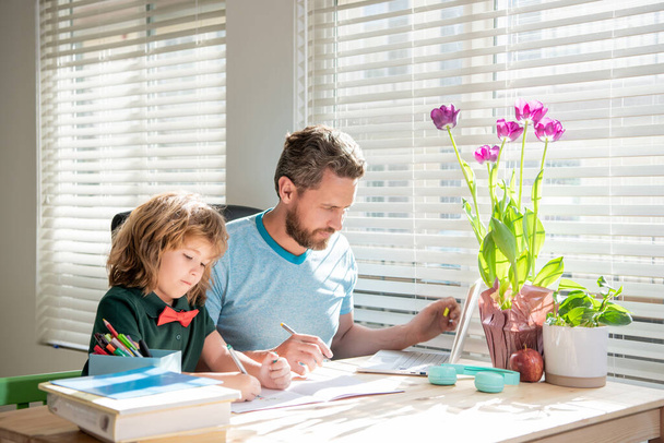 bärtiger Vater schreibt Hausaufgaben mit seinem Sohn im Klassenzimmer, Familientag - Foto, Bild