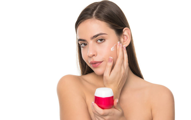 mujer joven aplicando crema para la piel de la cara aislada sobre fondo blanco, hábito diario - Foto, imagen