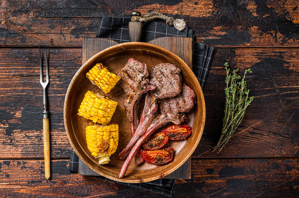 BBQ Roasted chops steaks of lamb, mutton in a wooden plate. Dark wooden background. Top view - Fotografie, Obrázek