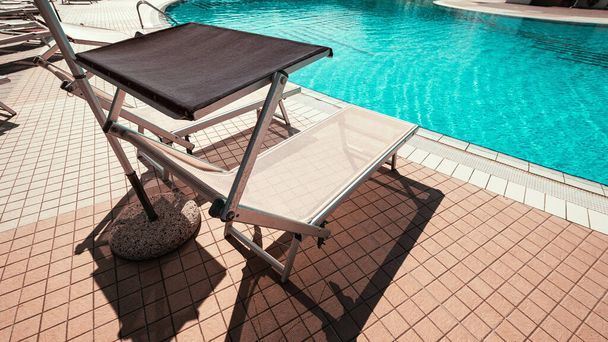 Een zonnebank. Zomerresortstoel, relaxlounge bij het luxe hotelzwembad. Strand ligstoel chaise. Vakantie zee rust zon tan concept - Foto, afbeelding