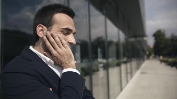 Handsome concerned businessman waiting for someone outdoors the office building. - Video, Çekim
