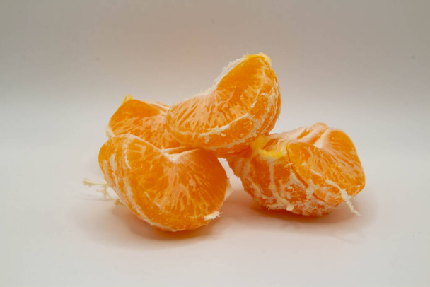Peeled tangerine slices lying on a white background - Fotografie, Obrázek