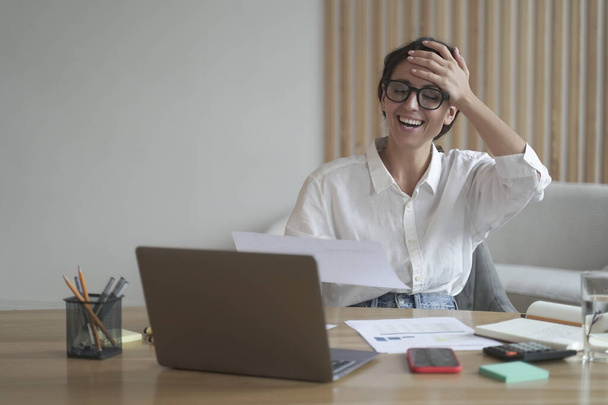 Sorrindo mulher de negócios italiana em óculos sentados na mesa em casa enquanto desfruta de videochamada online - Foto, Imagem