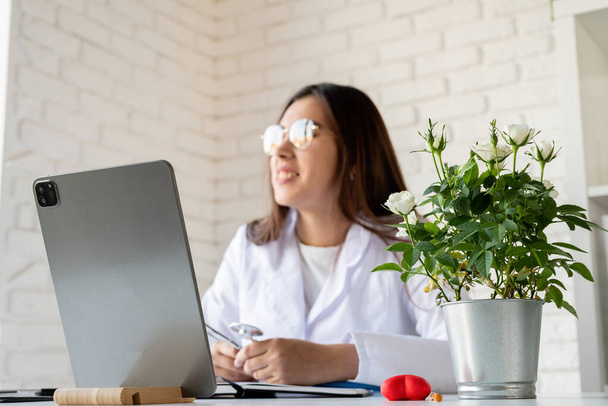 Healthcare, insurance concept. Young doctor woman with stethoscope having online call or consulting, doctor working online from home using digital tablet - Photo, Image