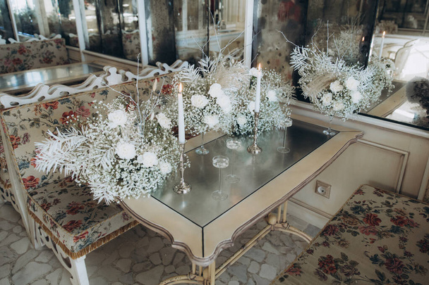 Karanfil çiçekleri, çingene çiçekleri ve şamdanların üzerindeki mumlarla dolu bir restoranda lüks bir düğün dekoru. - Fotoğraf, Görsel