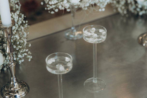 Luxury wedding decor on a table in a restaurant with carnation flowers, gypsophila flowers and candles on candlesticks - Фото, зображення