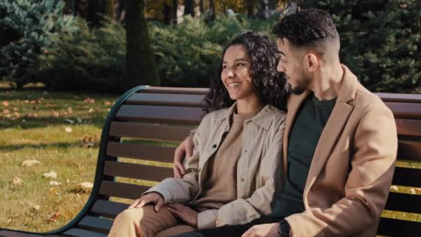 Весела іспаномовна пара рідко спілкується, сидячи на лавці в осінньому міському парку молодий бородатий хлопець обіймає привабливу кучеряву дівчину безтурботним спілкуванням на відкритому повітрі жінка вказує на палець подружжя щасливо посміхається
 - Кадри, відео