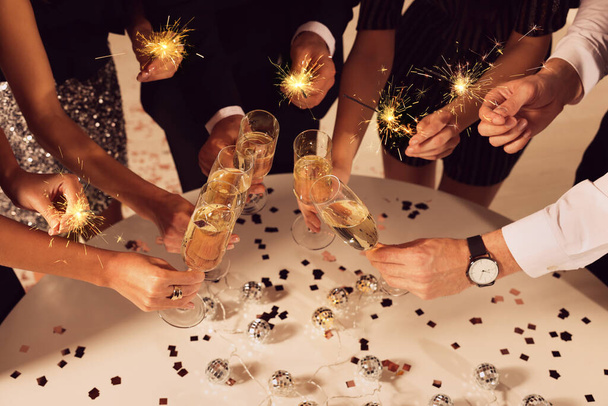 Amigos batendo copos de vinho espumante dentro de casa, close-up. Celebração de Ano Novo - Foto, Imagem