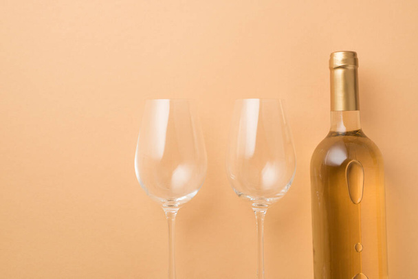 Bovenaanzicht foto van Sint Valentijnsdag decoraties fles witte wijn en twee wijnglazen op geïsoleerde pastel beige achtergrond met copyspace - Foto, afbeelding