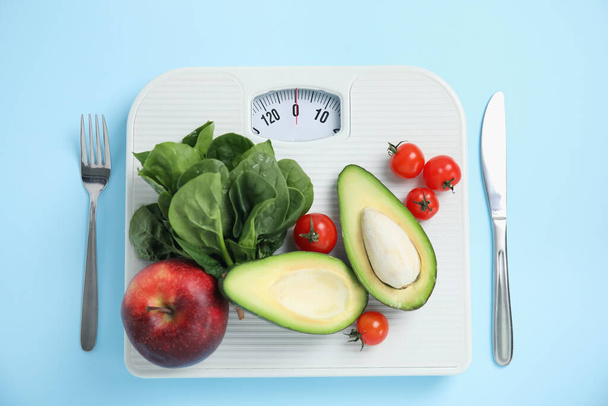 Scales, healthy food and cutlery on light blue background, flat lay - Фото, зображення