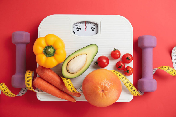 Flat lay composition with scales and healthy food on red background - Foto, Imagem