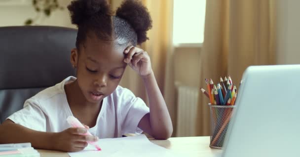 Серьезная сосредоточенная маленькая девочка африканский ребенок смотрит видео урок рисования на онлайн учитель репетитор повторяет рисует на бумаге с маркером, дистанционное обучение концепции дома во время пандемии карантина - Кадры, видео