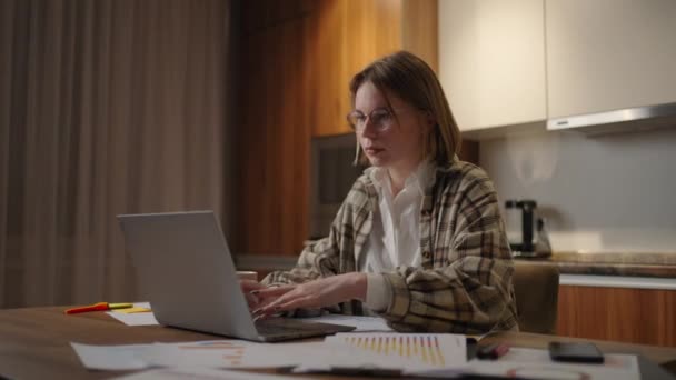 зріла бізнес-леді працює з дому, зосереджена жінка працює зі своїм ноутбуком і паперовими документами, сидячи на кухні вдома. додаток для ноутбуків обчислити витрати, витрати, оцінити бюджет проекту
 - Кадри, відео