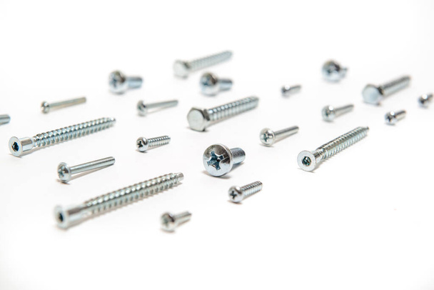 A lot of metal silver screws on white background - Foto, afbeelding