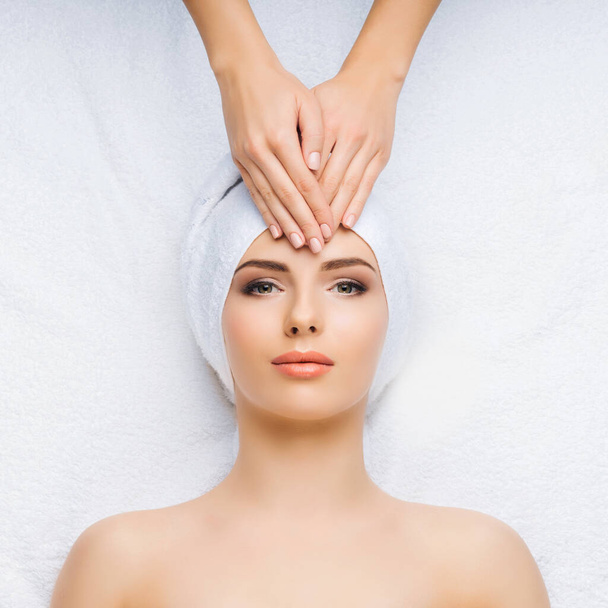 Young and healthy woman gets massage treatments for face, skin and neck in the spa salon. Health, wellness and rejuvenation concept. - Φωτογραφία, εικόνα