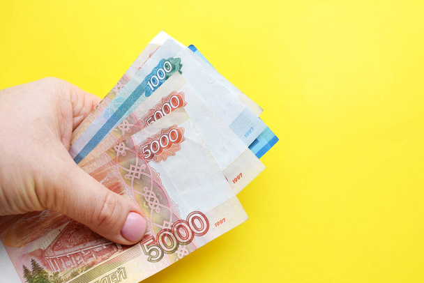 Russian ruble banknotes in a female hand on a yellow background. Copy space. - Foto, imagen