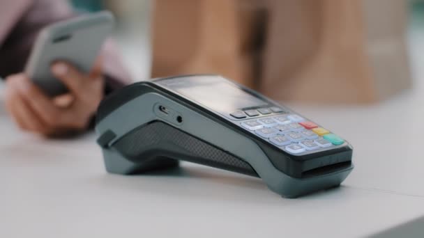 Γυναίκα στο check-in γραφείο στο μετρητή πληρώνει με smartphone μέσω NFC ανέπαφη πληρωμή από κινητό τηλέφωνο σε μπαρ καφέ αγορά προϊόντων διατροφής πληρώνουν με κάρτα από το τηλέφωνο γκρο πλαν εστίαση σε τερματικό - Πλάνα, βίντεο