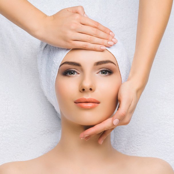 Young and healthy woman gets massage treatments for face, skin and neck in the spa salon. Health, wellness and rejuvenation concept. - Valokuva, kuva